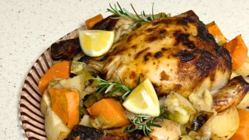 Roasted piece of chicken surrounded by roasted vegetables