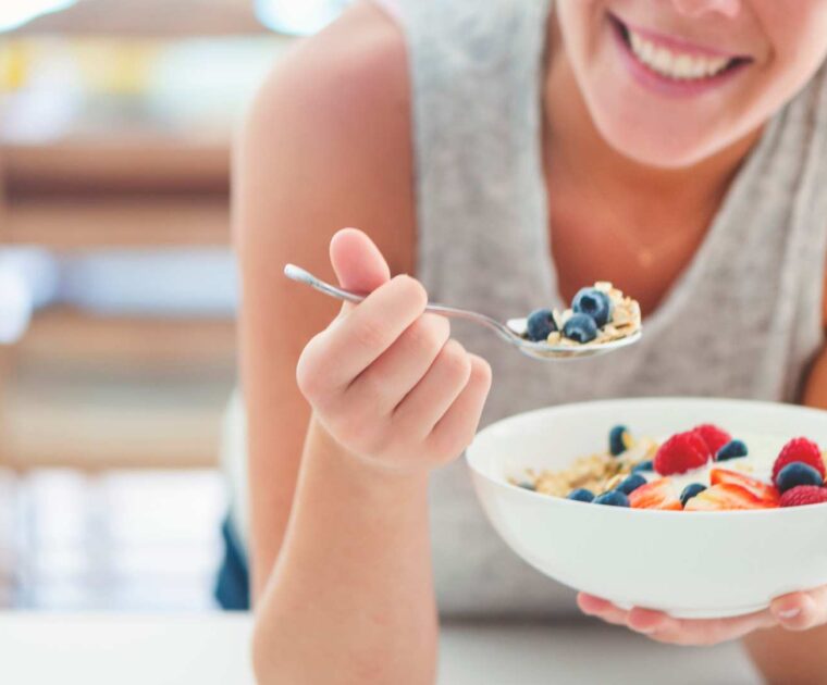 Woman eating bowl of fruit and cereal