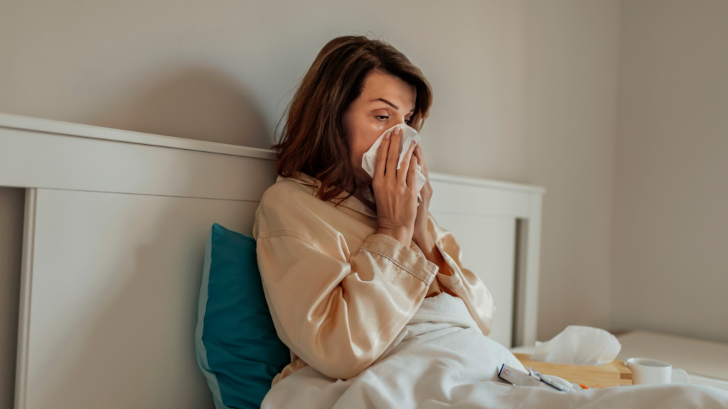 A person blowing their nose while sitting up in bed