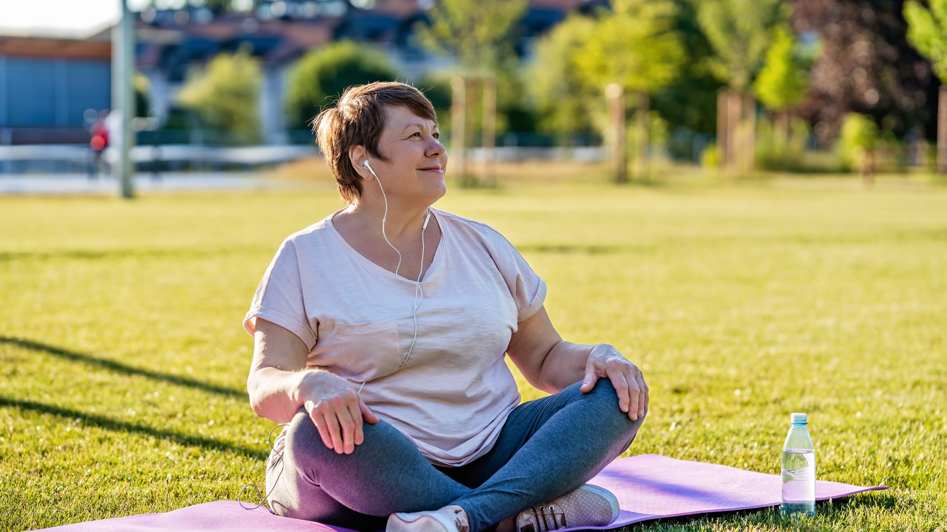 A woman sitting on a yoga mat in a park
