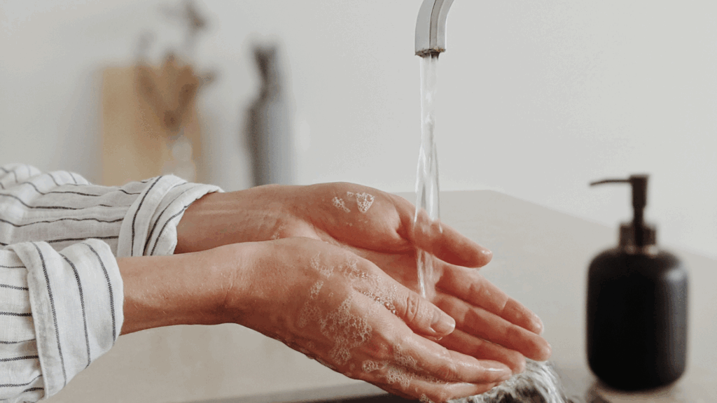 A close up shot of a woman washing her hands under a tap with soap