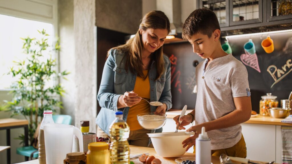 A woman teaching her son cooking skills in the kitchen
