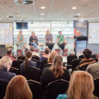 A crowd of people watching a panel discussion at the ABC Conference