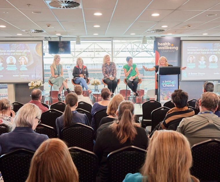 A crowd of people watching a panel discussion at the ABC Conference