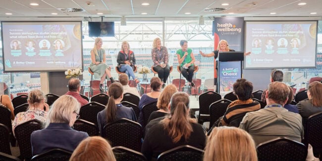 A group of people watching a panel talk on stage at the ABC conference 2023