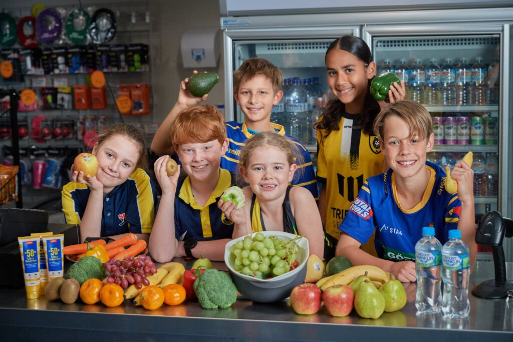 6 primary school children pose with fresh fruit and vegetables