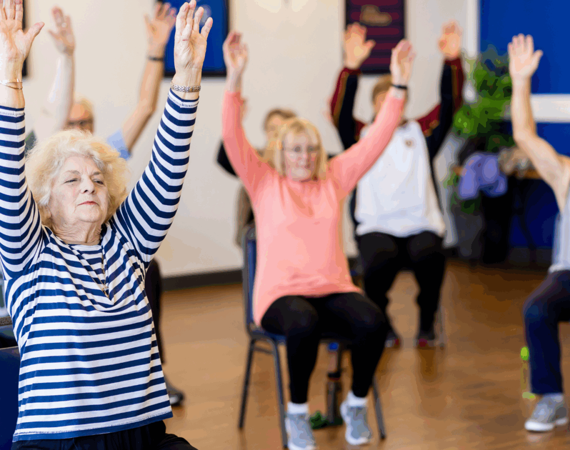 People sitting in chairs during an exercise class.