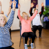 People sitting in chairs during an exercise class.