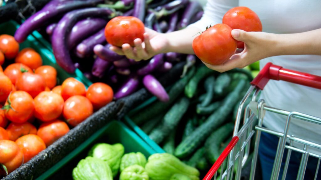Person adding fresh tomatoes to shopping trolley