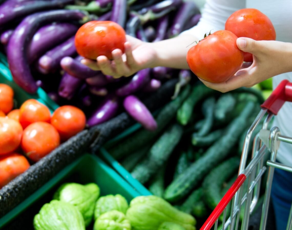 Person adding fresh tomatoes to shopping trolley