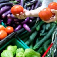 Person adding fresh tomatoes to shopping trolley