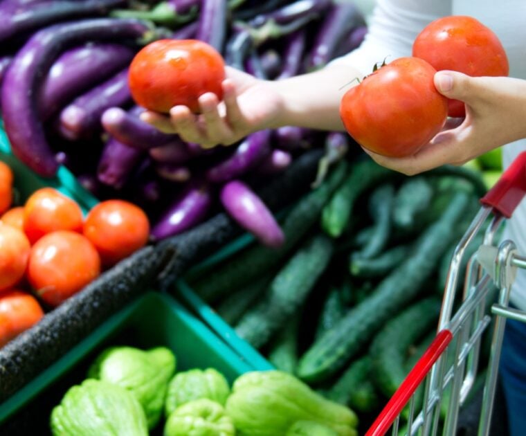 Person adding fresh tomatoes to shopping trolley