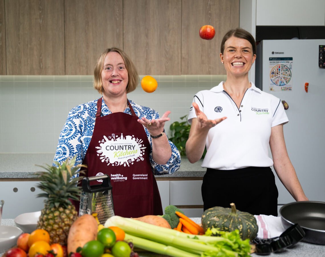 Two people in a kitchen with fresh fruit and veggies