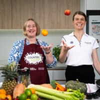 Two people in a kitchen with fresh fruit and veggies