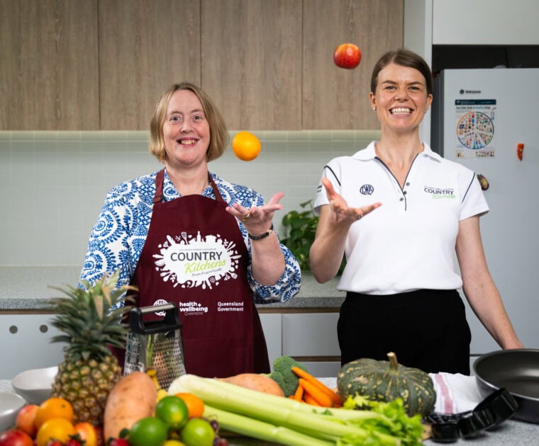 Two people in a kitchen with fresh fruit and veggies