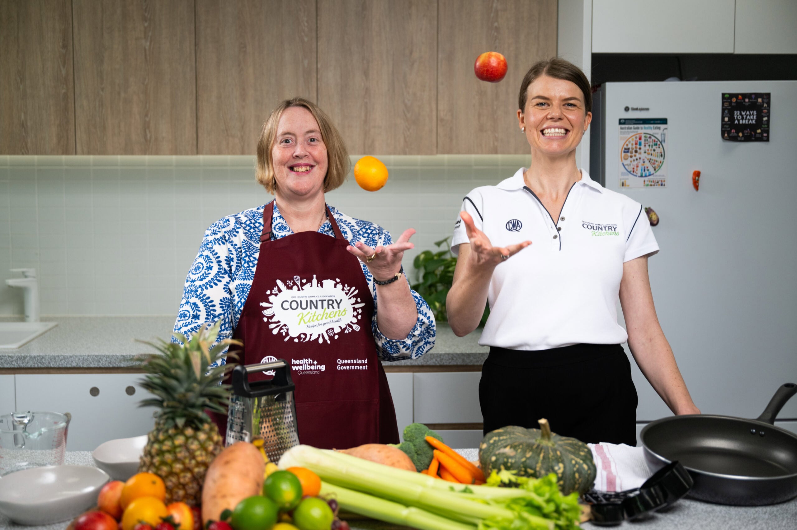 Two people in a kitchen with fresh fruit and veggies