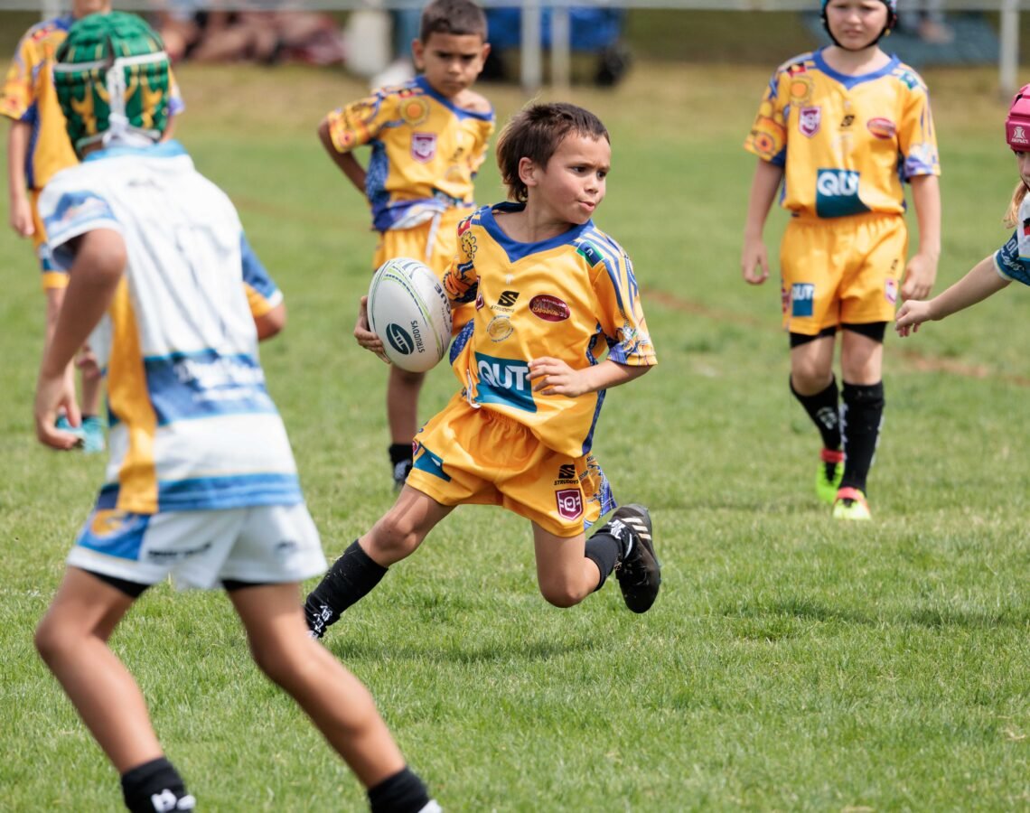 Young person holding NRL ball on a field.