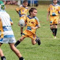 Young person holding NRL ball on a field.