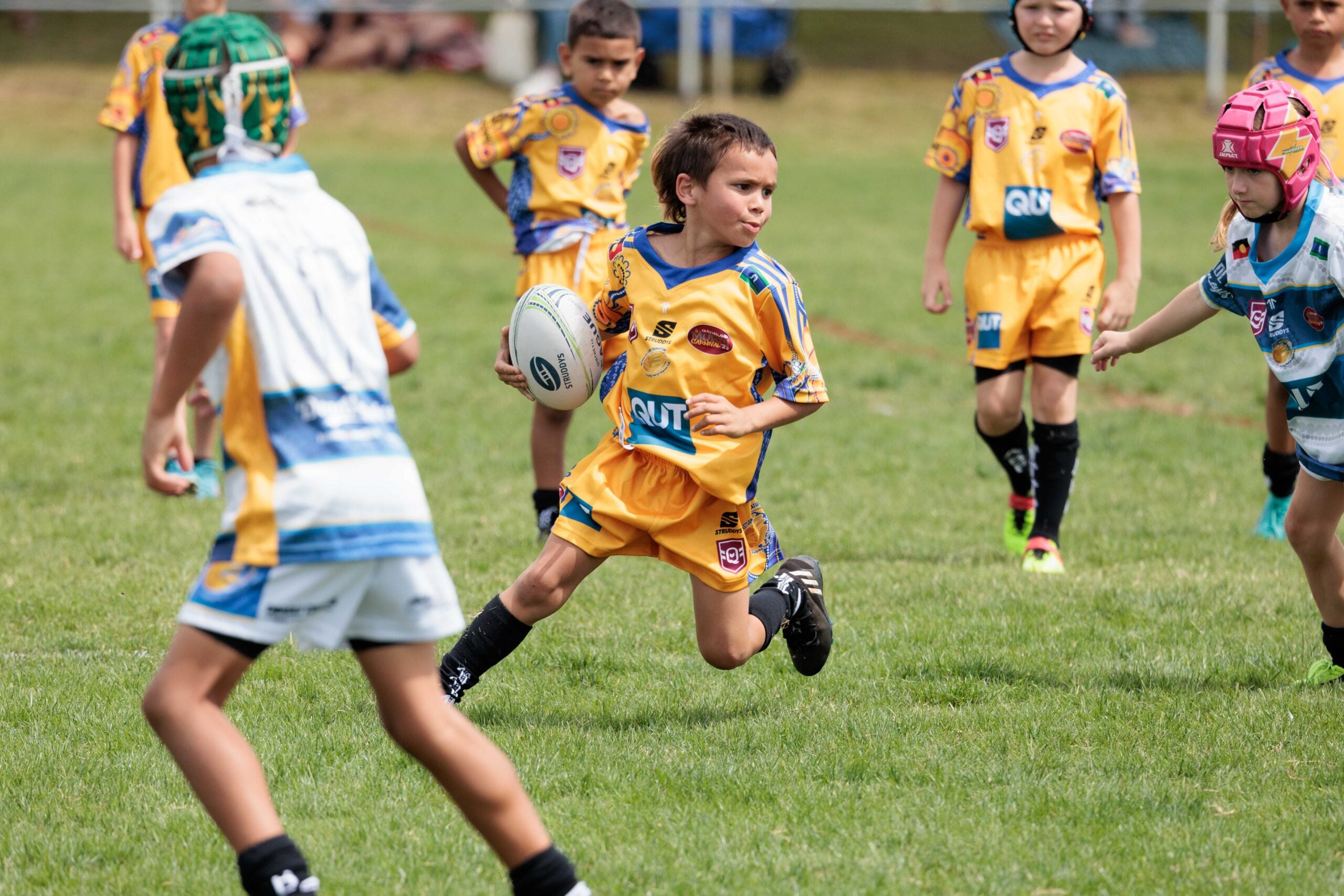 Young person holding NRL ball on a field.