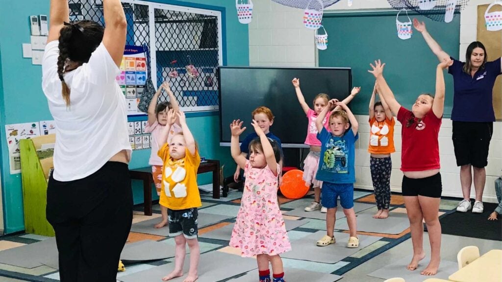 Young children participate in a group yoga class at school