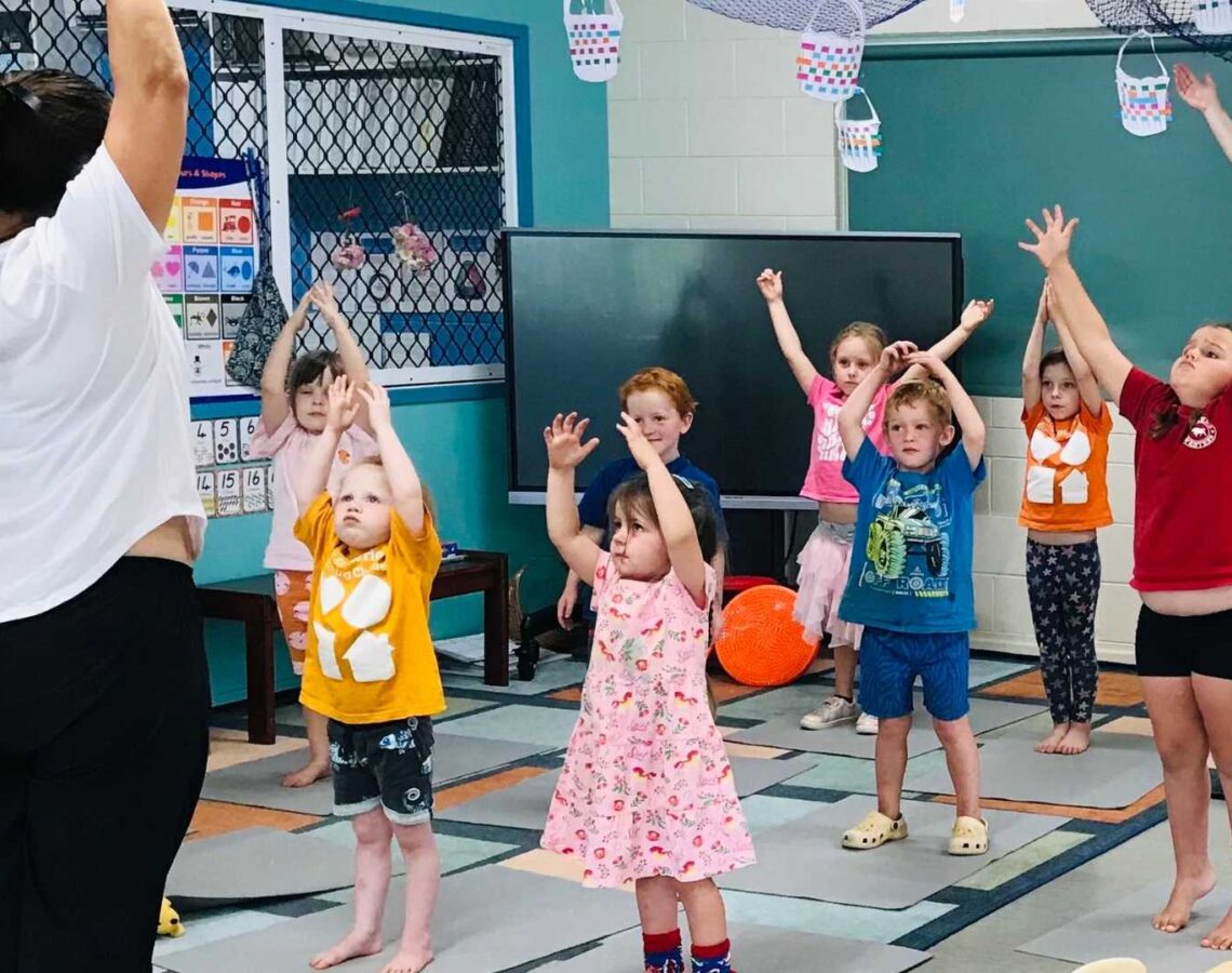 Young children participate in a group yoga class at school