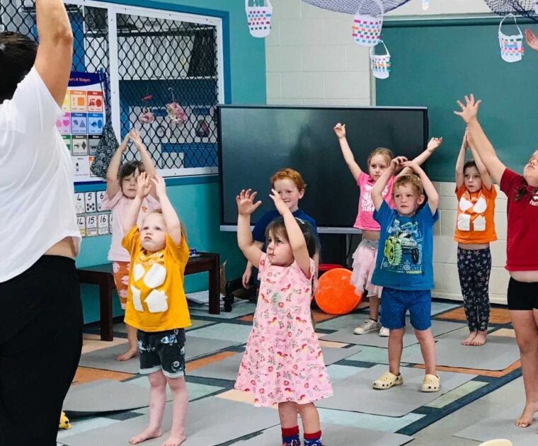 Young children participate in a group yoga class at school