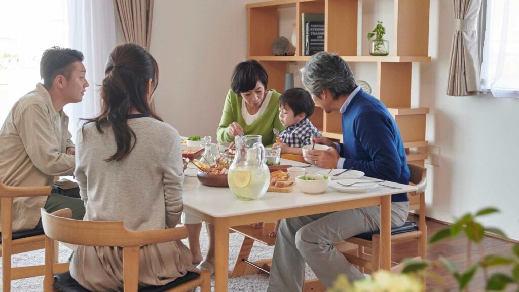 Family of 5 sits at a dining table eating together