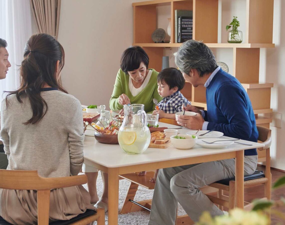 Family of 5 sits at a dining table eating together