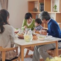 Family of 5 sits at a dining table eating together