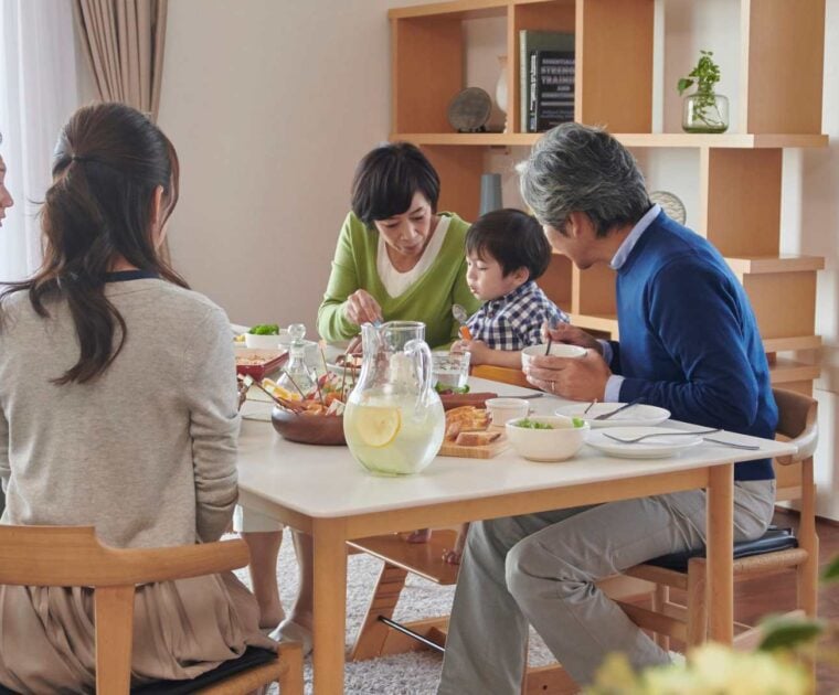 Family of 5 sits at a dining table eating together