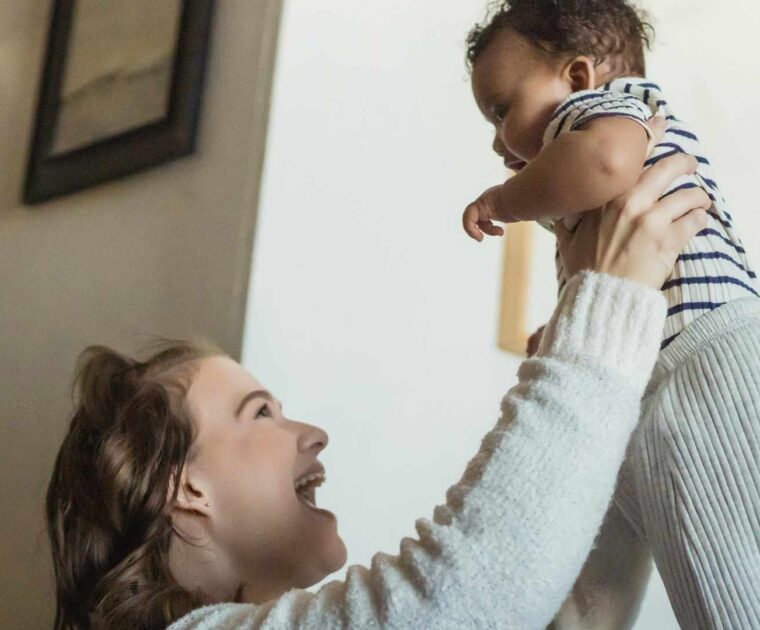 Smiling mum lifting baby up