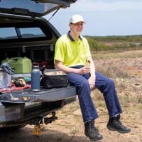 Tradie sits on the back of his ute holding a salad wrap for lunch