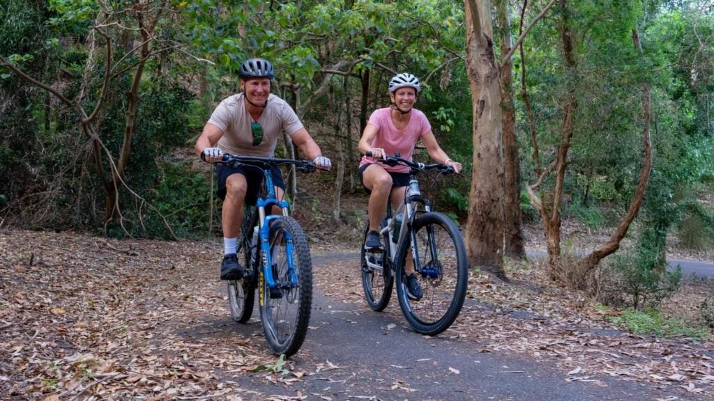 Man and woman mountain biking through bushland