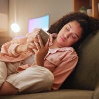 Woman sits on couch scrolling her phone