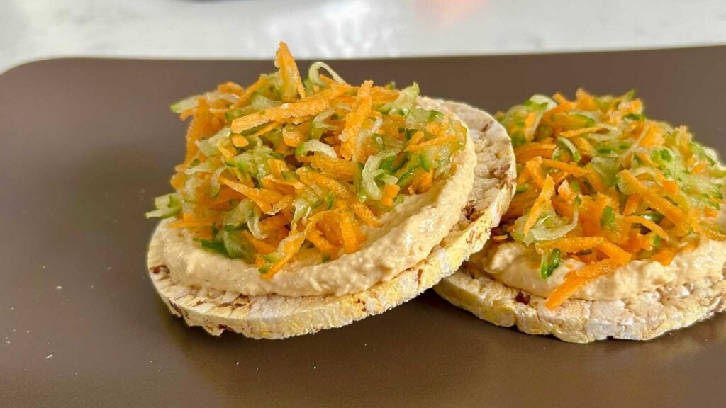 Rice cakes topped with hummus and grated carrot and cucumber