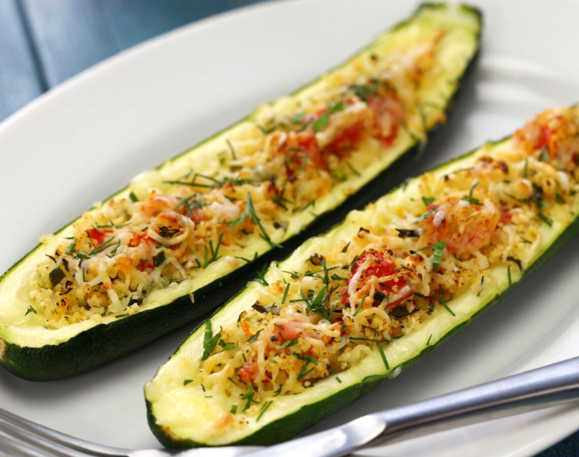 Two stuffed zucchini slices topped with vegetables, cheese and fresh herbs