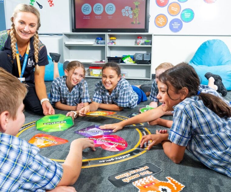 School children lay on the carpet in the classroom interacting in a circle with an adult