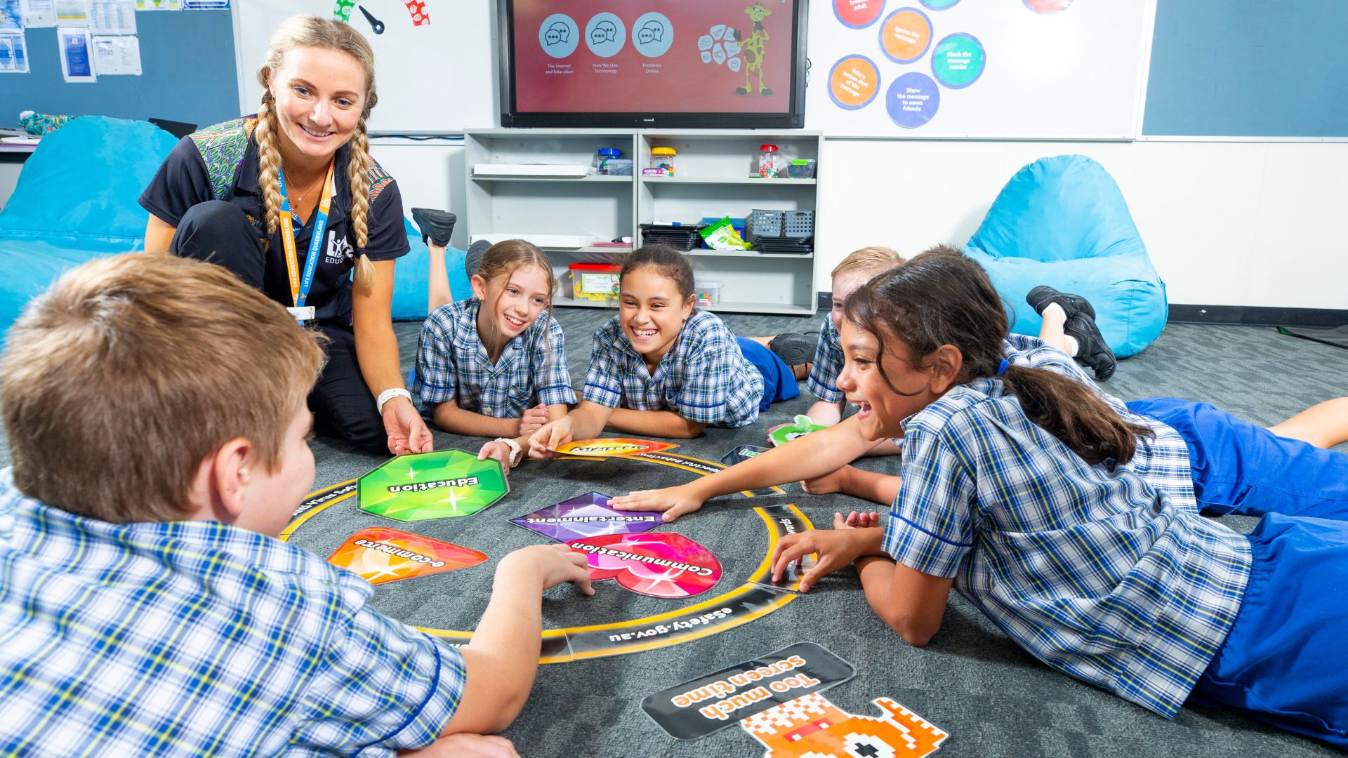 School children lay on the carpet in the classroom interacting in a circle with an adult