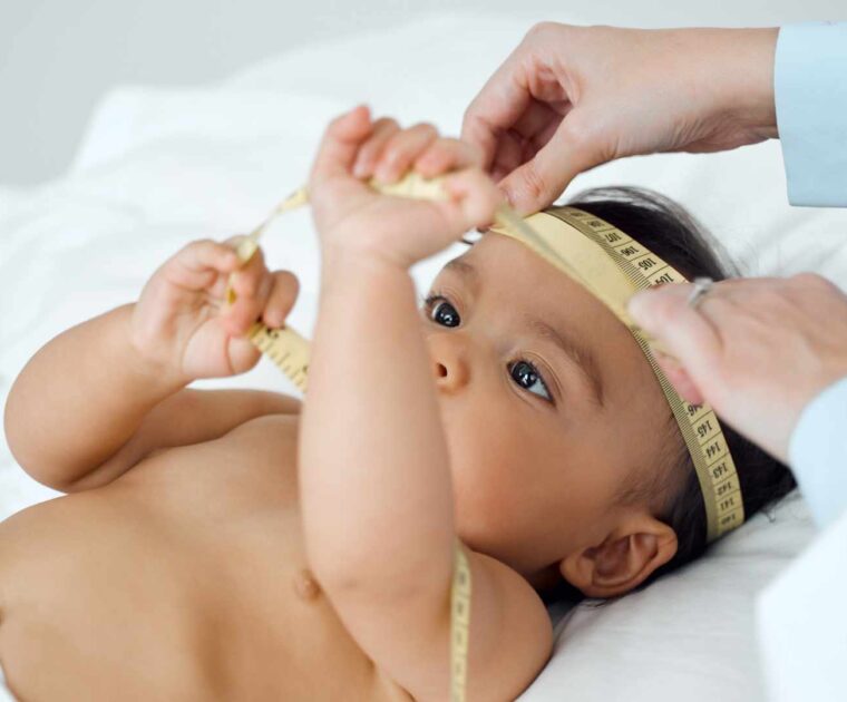 A health professional measuring baby's head