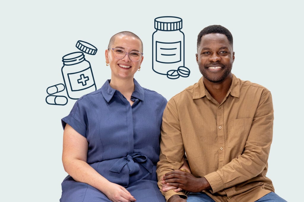 Woman and man sit together holding hands and smiling to camera
