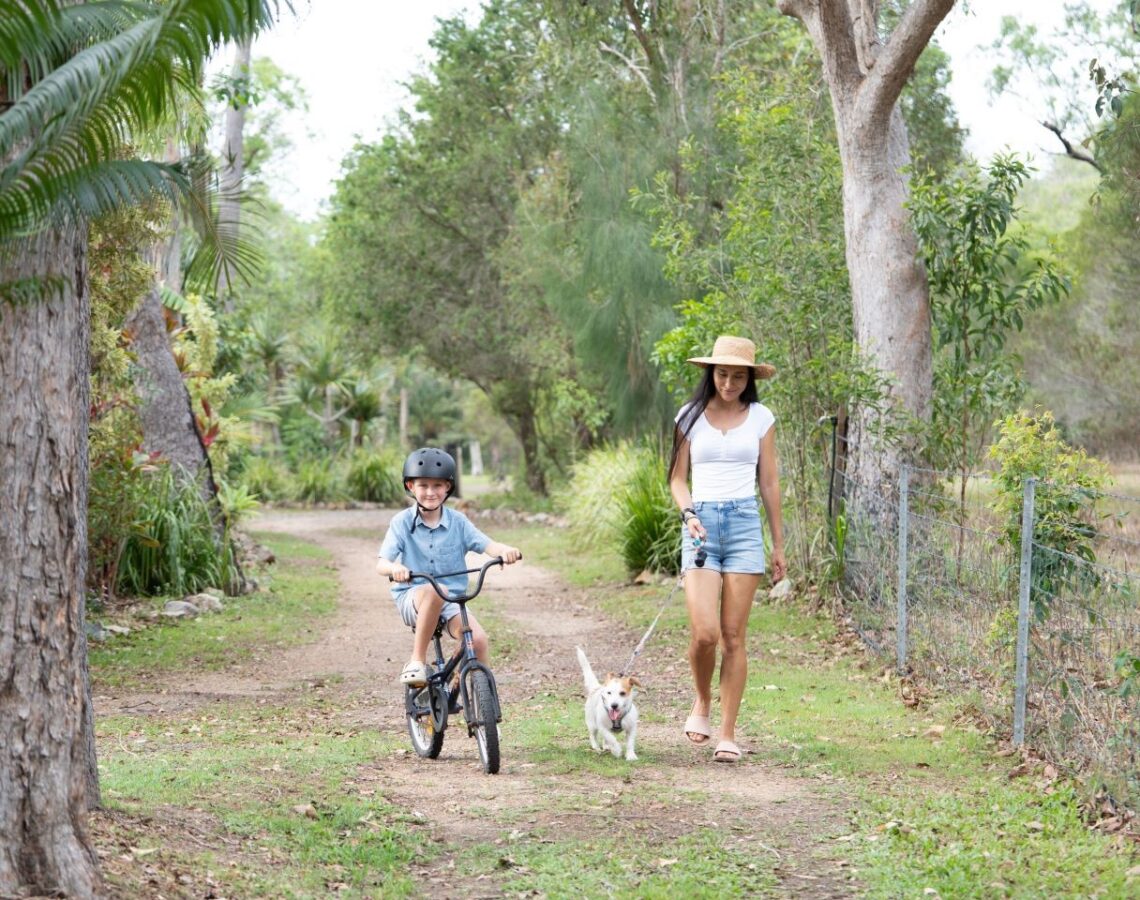 Woman walking her dog with her son on a bike.
