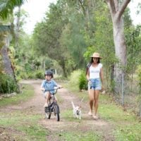 Woman walking her dog with her son on a bike.