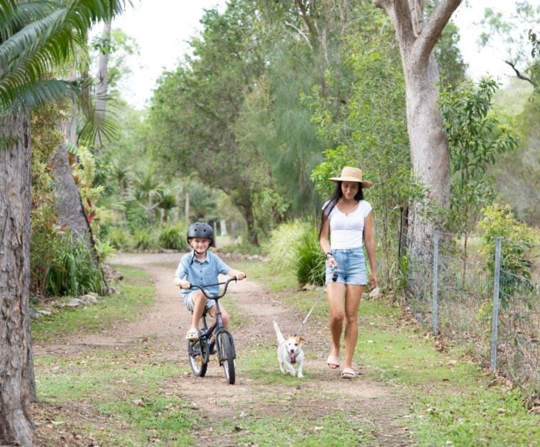 Woman walking her dog with her son on a bike.