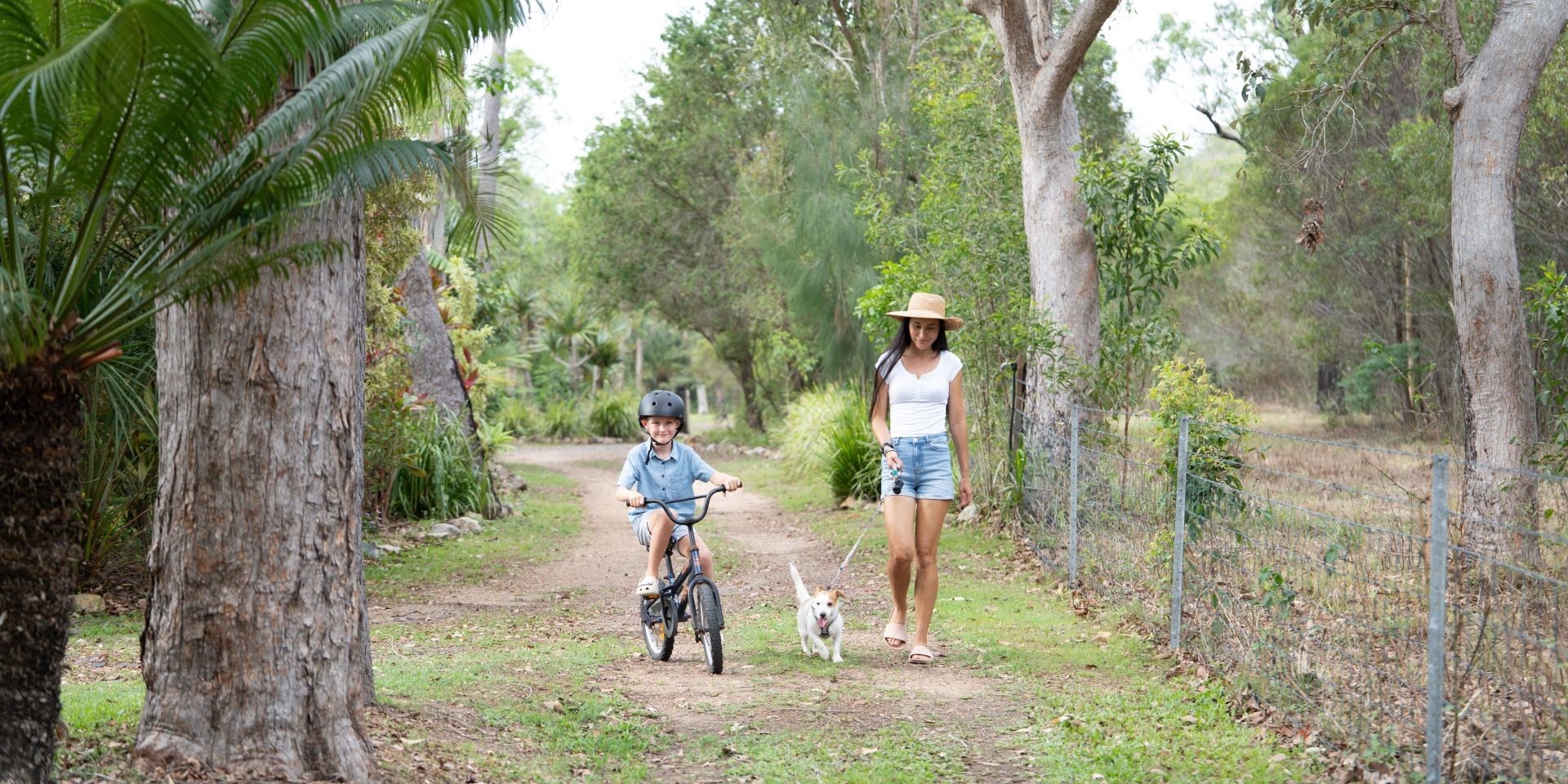 Woman walking her dog with her son on a bike.