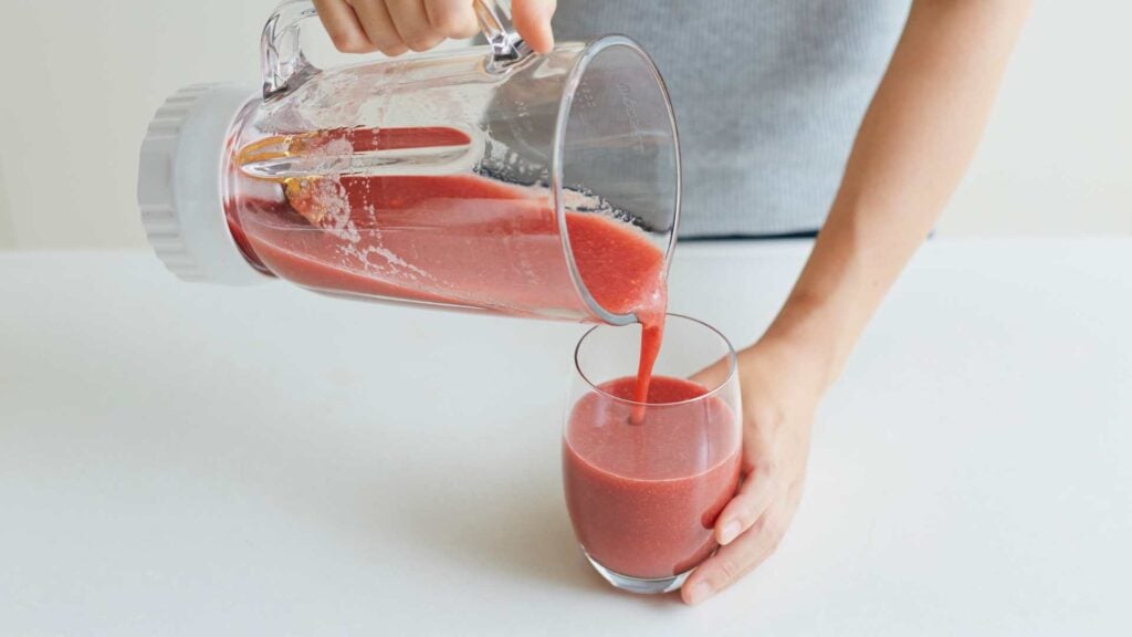 Fruit and vegetable smoothie being poured into a glass