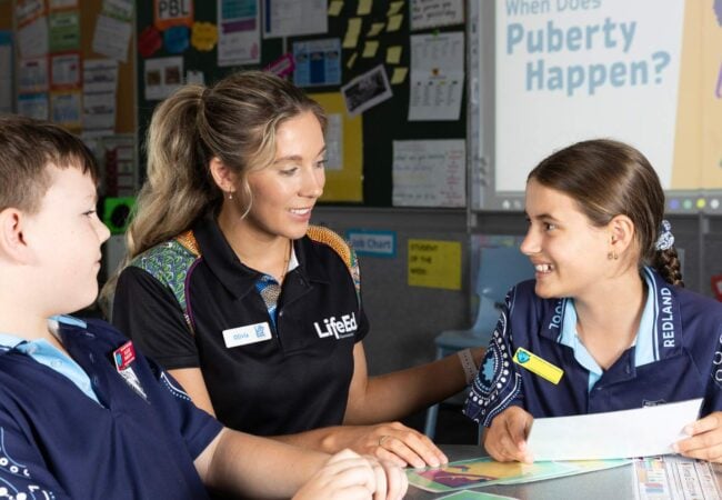 Woman teaches primary school boy and girl about puberty