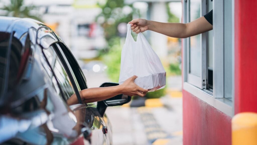 Customer receiving takeaway food out of a drive thru window