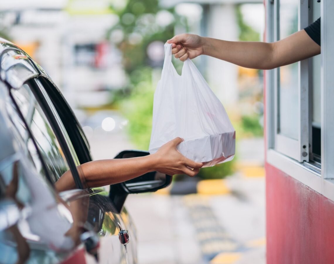 Customer receiving takeaway food out of a drive thru window