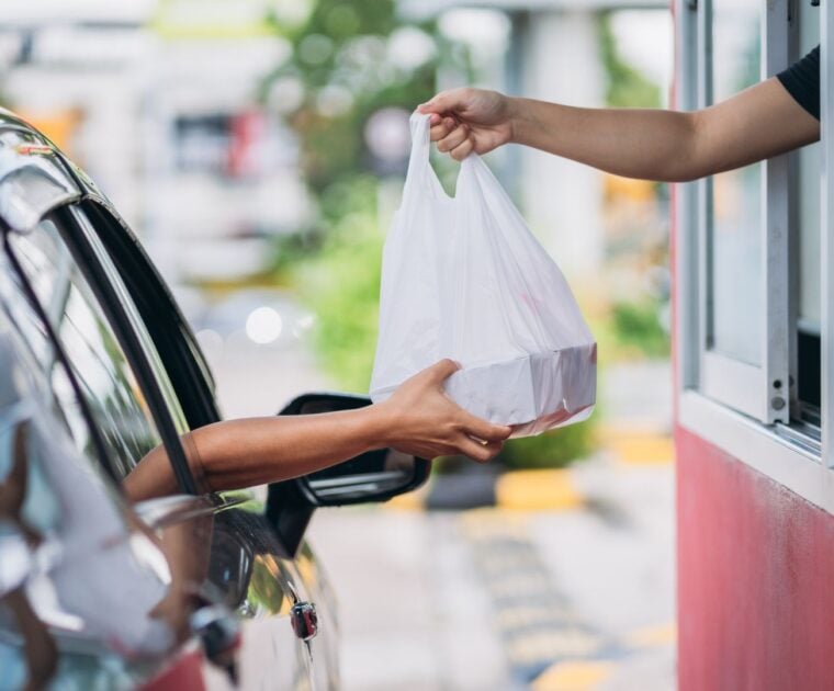 Customer receiving takeaway food out of a drive thru window