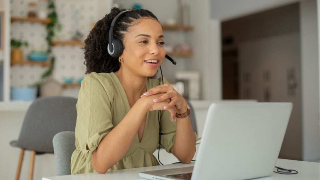 Woman wears headset and sits in front of a laptop